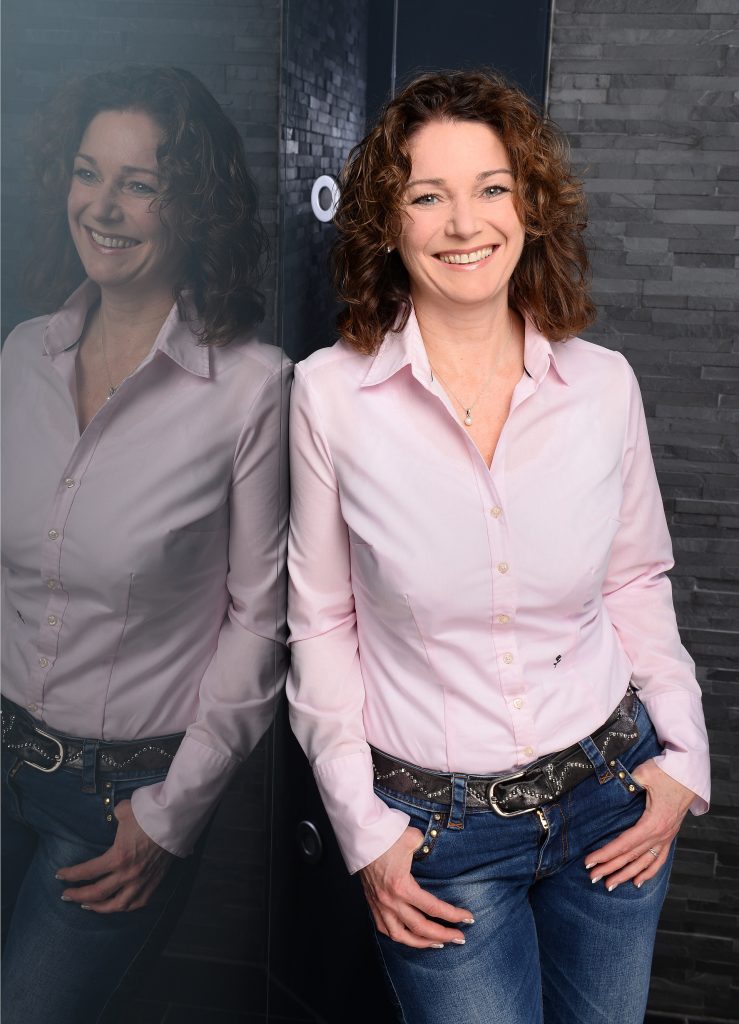 Petra Isabel Schlerit, Top 100 Trainerin und Businesscoach, natuerliche Haltung in rosa Bluse am Spiegel